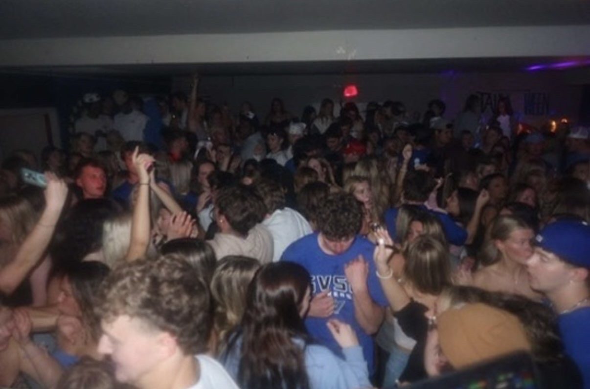 A packed frat party crowd with hands in the air